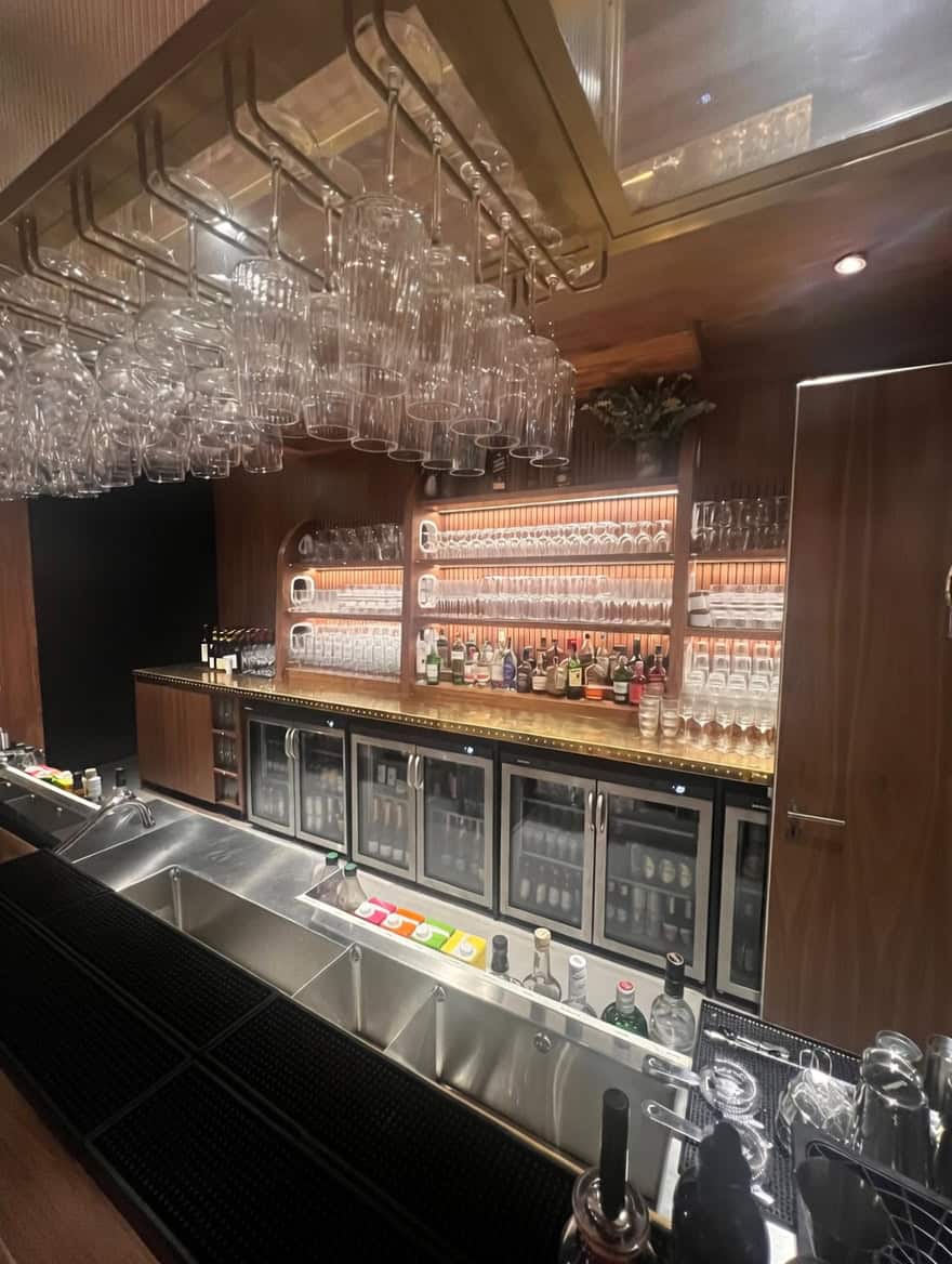 Custom bar gantry with overhead glass rack and brass detailing at Everton Stadium hospitality bar