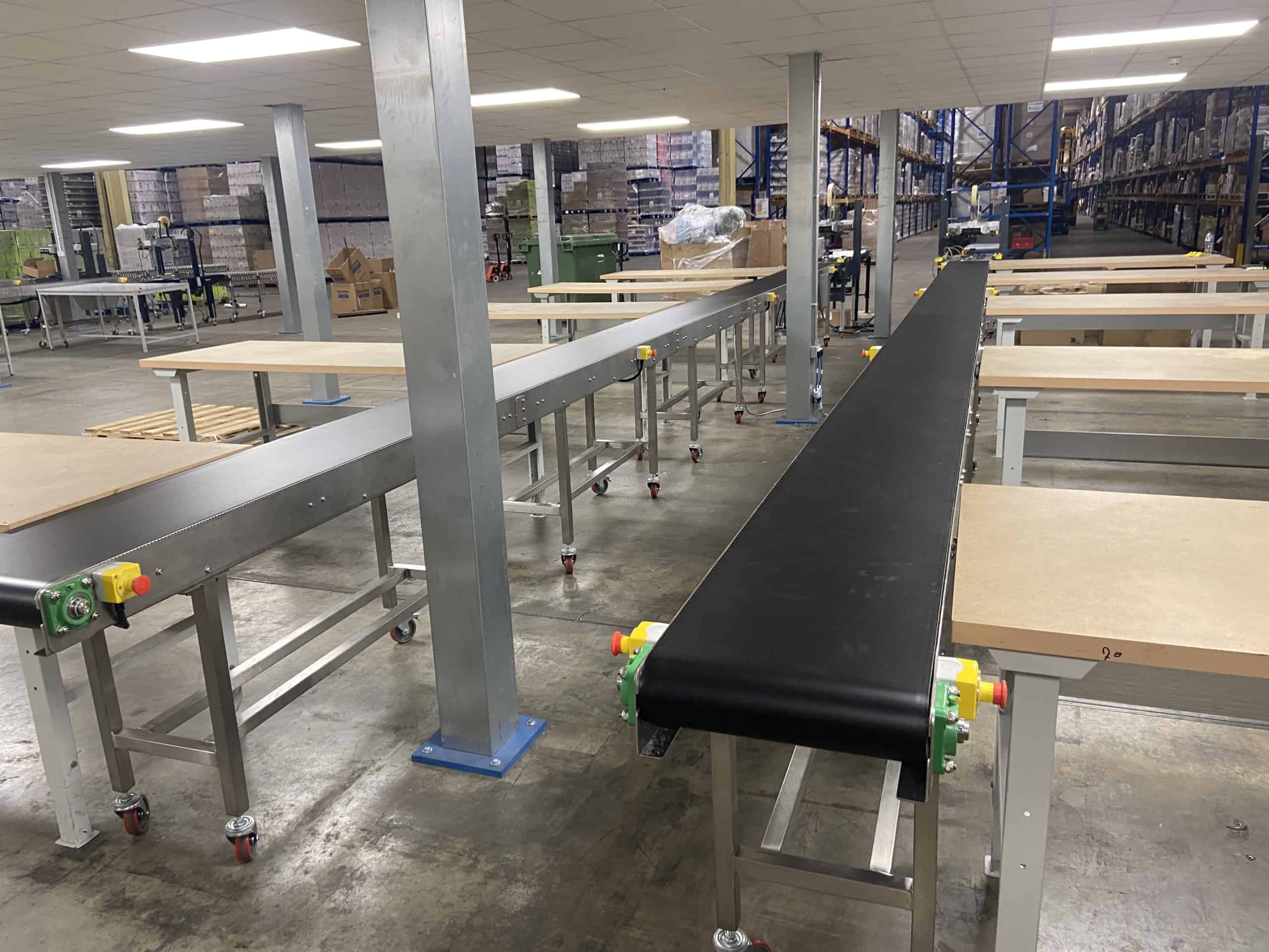 Stainless steel belt conveyor system installed in warehouse distribution centre with packing stations