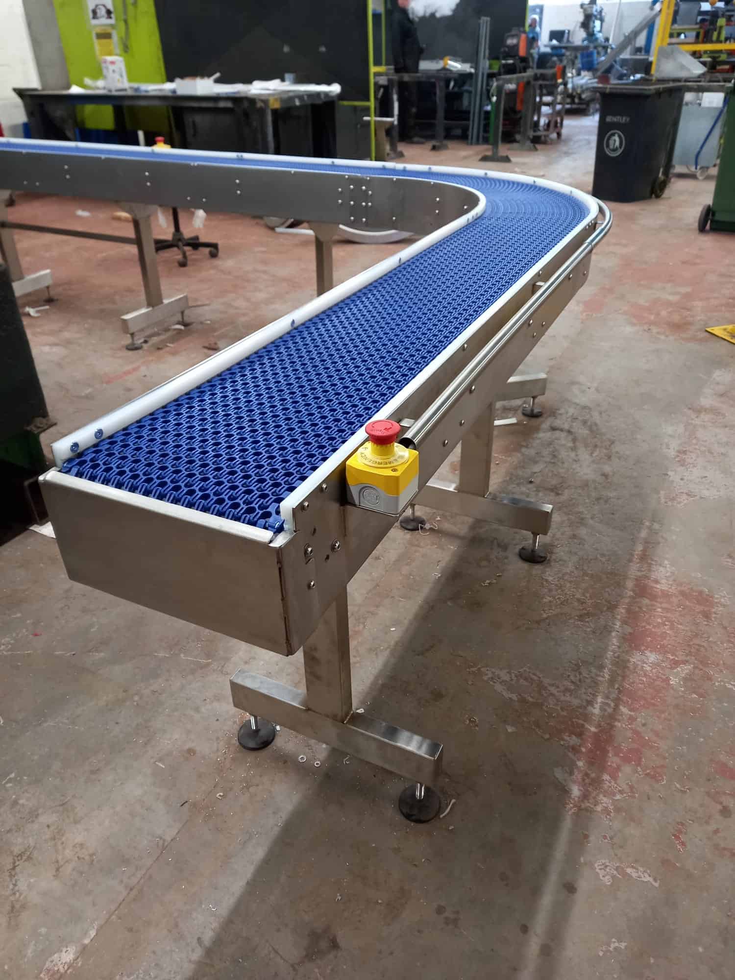 Stainless steel modular belt conveyor with 90-degree curve and emergency stop manufactured by MorFabrication