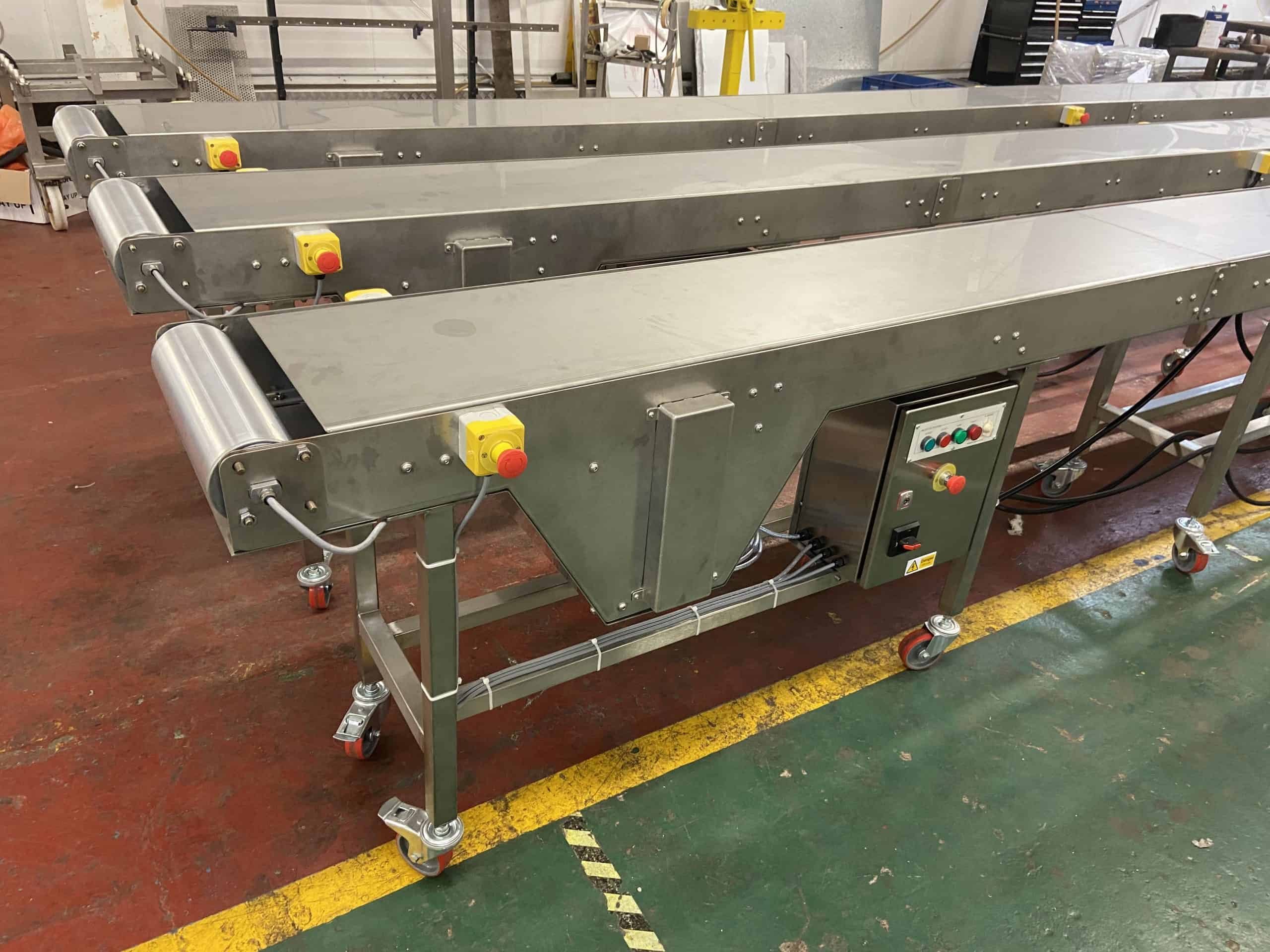 Multi-lane stainless steel belt conveyor system with integrated control panel manufactured by MorFabrication