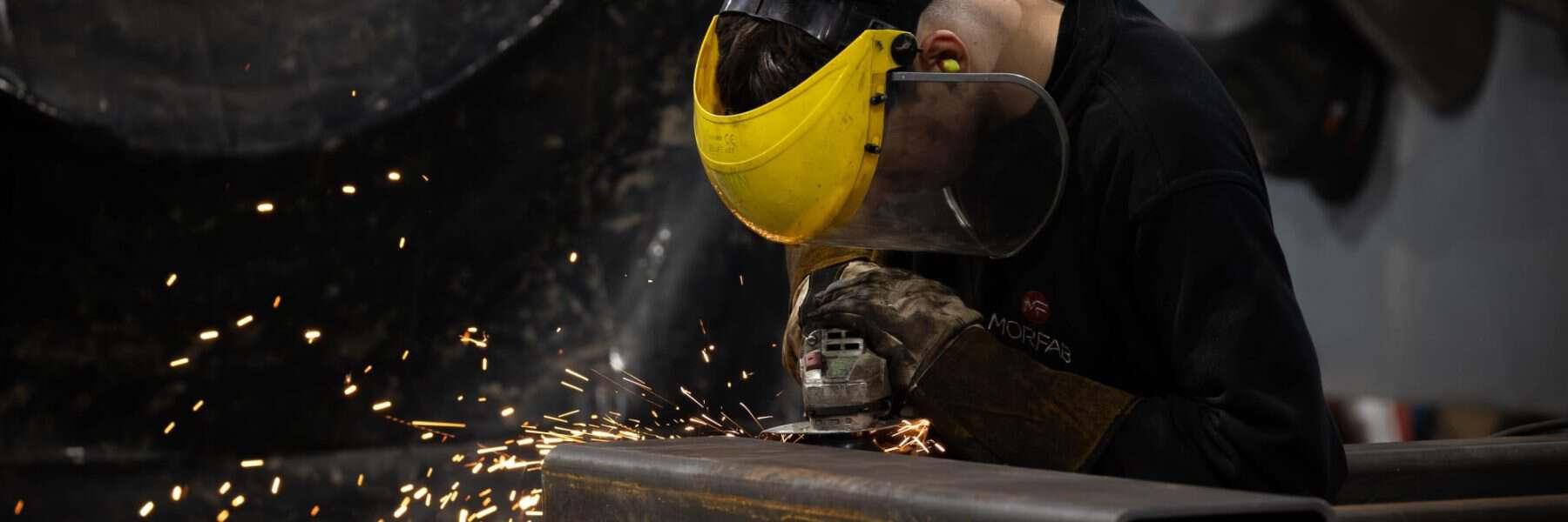 MorFab fabricator grinding a welded steel box section in our Washington workshop