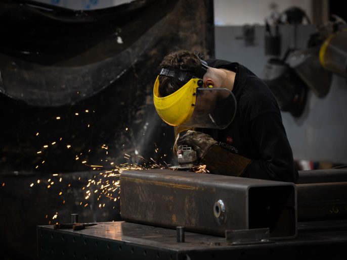 MorFab fabricator grinding a welded steel box section in our Washington workshop