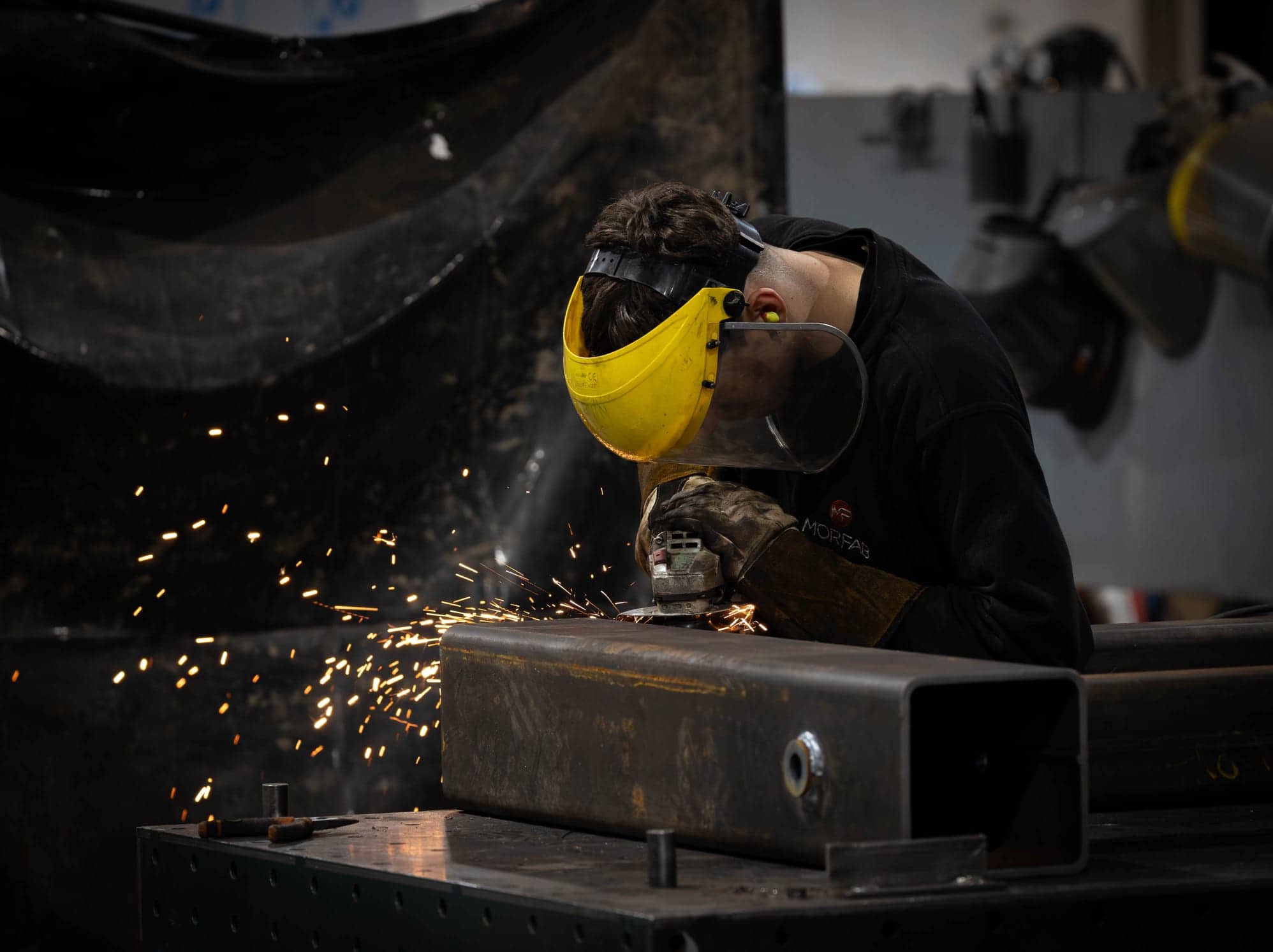 MorFab fabricator grinding a welded steel box section in our Washington workshop